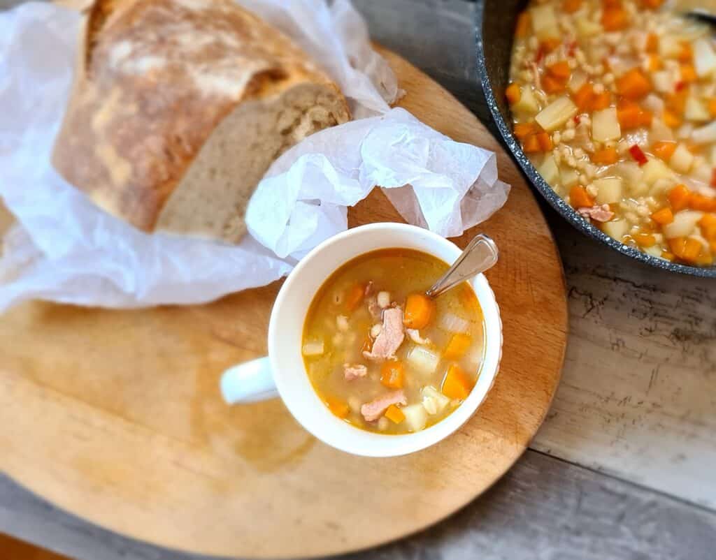 Spicy Scotch broth soup served in a cup with crusty bread