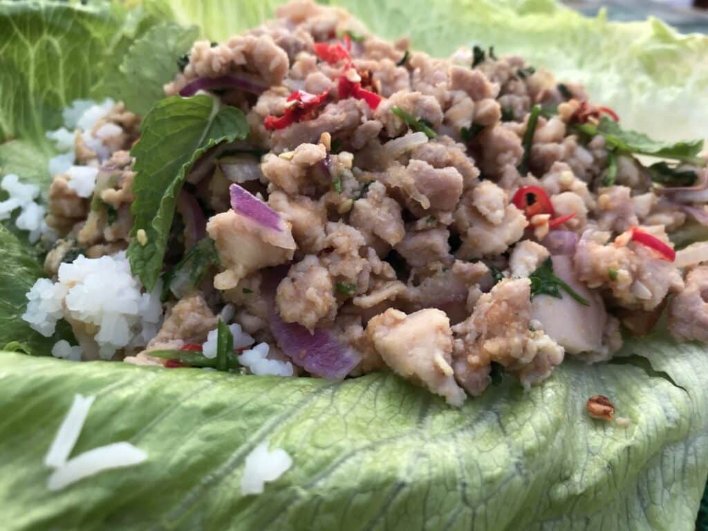 Close-up of larb isaan, served with Jasmine rice and greens
